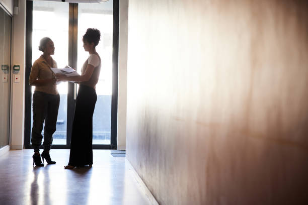 istock Businesswomen discussing paperwork in an office corridor 1412633644