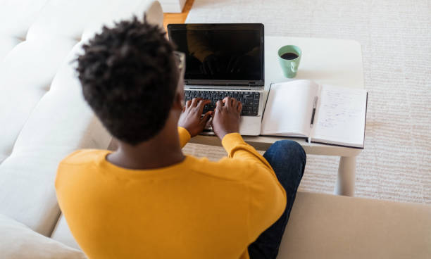 istock Smiling black man using laptop at home in living room. 1412633752