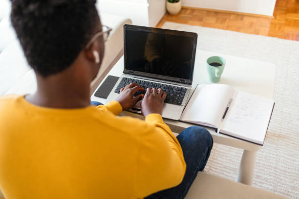 istock Handsome African American man working on laptop computer while sitting behind desk in cozy living room. 1412633753