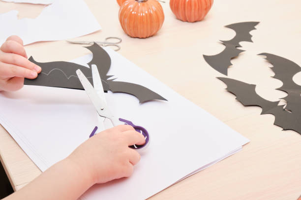 istock Halloween handmade decor. Child makes paper bat 1412635056