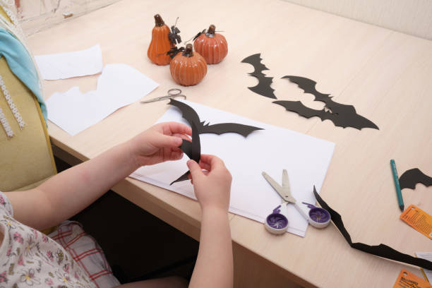 istock Halloween handmade decor. Child makes paper bat 1412635059