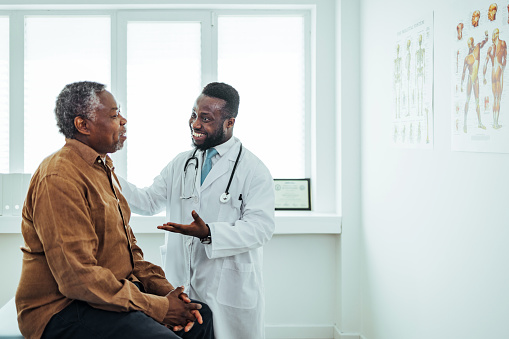 A male doctor chats to an elderly male patient.