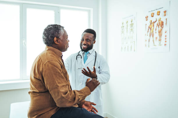 paciente do sexo masculino sênior conversa com profissional de saúde - doctors office examination room examination table office - fotografias e filmes do acervo