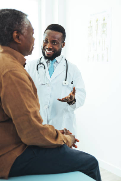african american senior man talks with his doctor - doctors office examination room examination table office imagens e fotografias de stock
