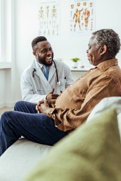 le médecin sourit et essaie d’encourager l’homme âgé triste - male doctor photos et images de collection