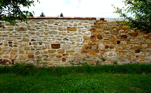 old stone wall is being reconstructed between two plots. the stones are dismantled and re-glued to cement mortar. stonemason builds a wall in park. the joints are repaired and bush, before, after, new, after, workflow, disintegrate, irregular, mortar