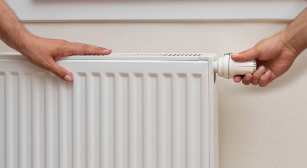 istock Man's hand adjusting the temperature of a radiator. 1412638265