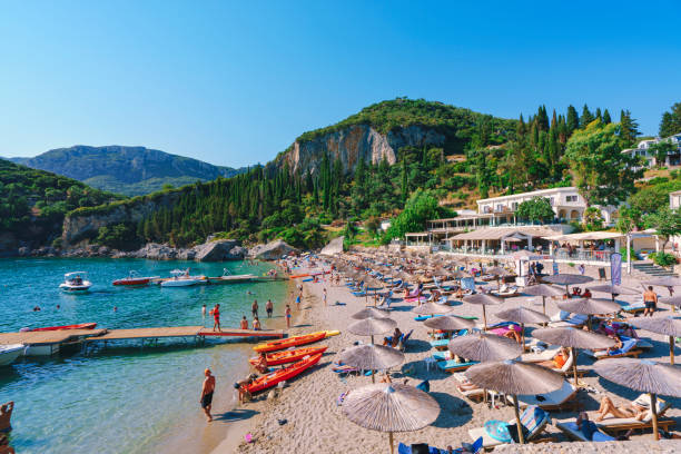 ギリシャのパライオカス�トリツァコルフ島のリラックスした人々とリアパデスビーチ - corfu greece sea beach ストックフォトと画像