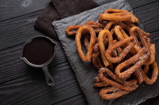 istock Homemade churros with chocolate on a dark wooden rustic background. 1412640508