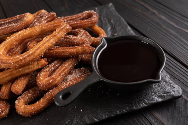 istock Homemade churros with chocolate on a dark wooden rustic background. 1412641294