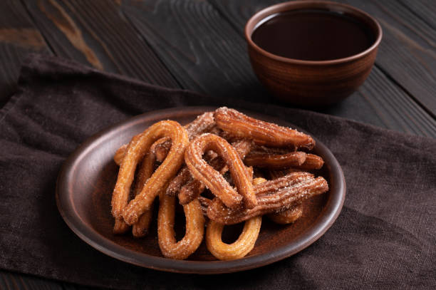 istock Homemade churros with chocolate on a dark wooden rustic background. 1412641296
