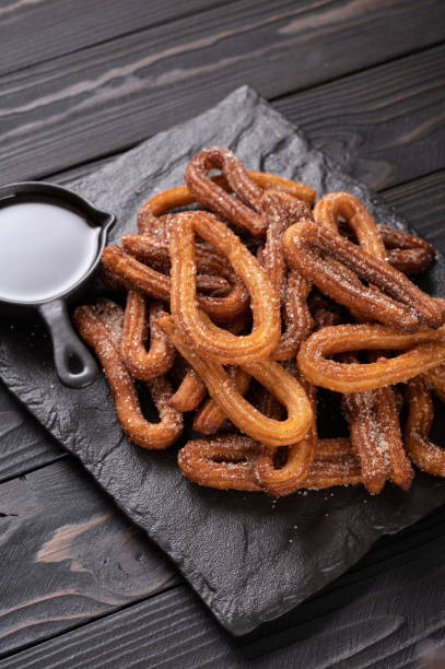 istock Homemade churros with chocolate on a dark wooden rustic background. 1412641331