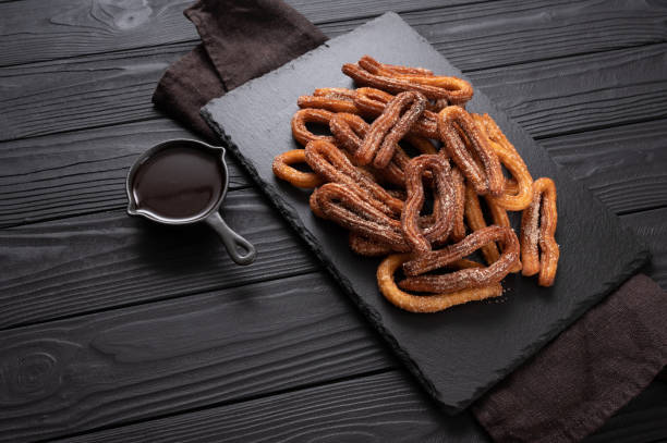 istock Homemade churros with chocolate on a dark wooden rustic background. 1412641366