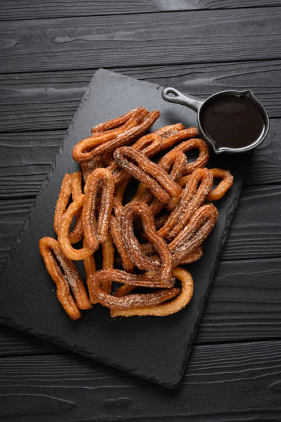 istock Homemade churros with chocolate on a dark wooden rustic background. 1412641396