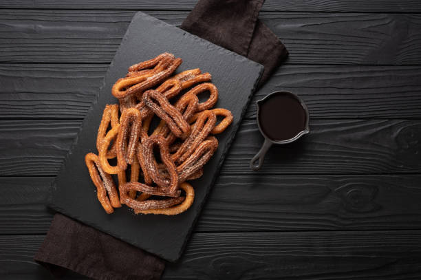 istock Homemade churros with chocolate on a dark wooden rustic background. 1412641410