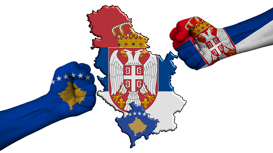 Serbia vs Republic of Kosovo. Two fists with national flags for military conflict, in the middle the geographical map of the two countries, on a white background