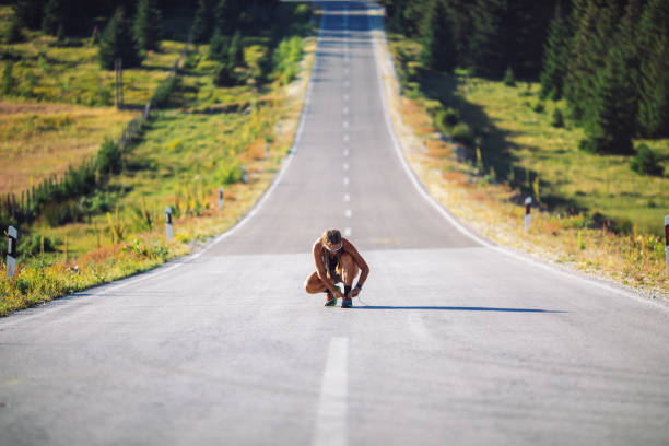 Mid adult woman jogging over empty road on mountain. She is fit and muscular, professional sky runner