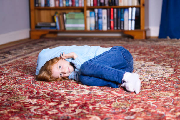 Red-haired girl resting on the carpet in the study.