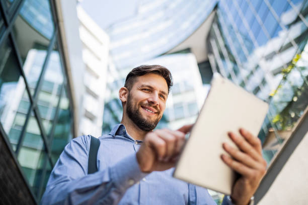 istock Businessman in front of office building using digital tablet and drinking coffee on the move 1412644740
