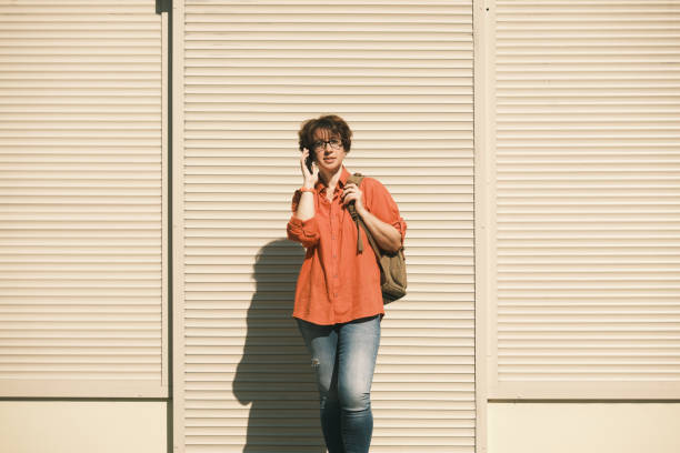 istock Woman is talking by phone standing next to the wall 1412647955