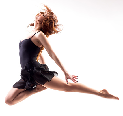 pretty modern slim hip-hop style teenage girl jumping dancing isolated on a white studio background. High quality photo