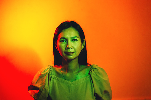 close-up portrait of Asian woman lit by green and red neon lights