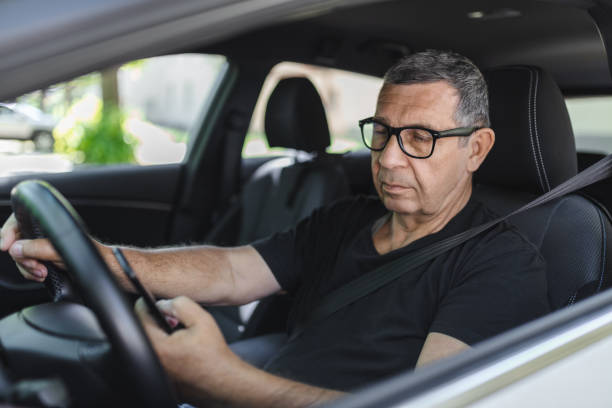 istock Senior in his 70s driving a car and using his mobile phone 1412653259