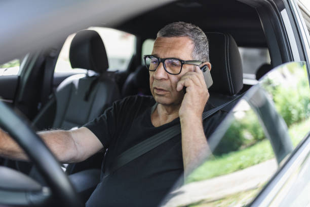 istock Senior in his 70s driving a car and using his mobile phone 1412653287