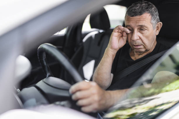 Tired pensioner in his 70s, dring in a car