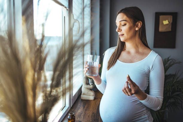 istock Pregnant woman taking pill at home. 1412653862