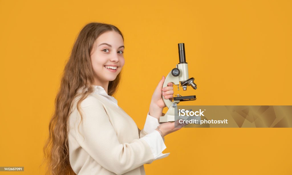 smiling kid with microscope on yellow background smiling kid with microscope on yellow background. Chemistry Stock Photo