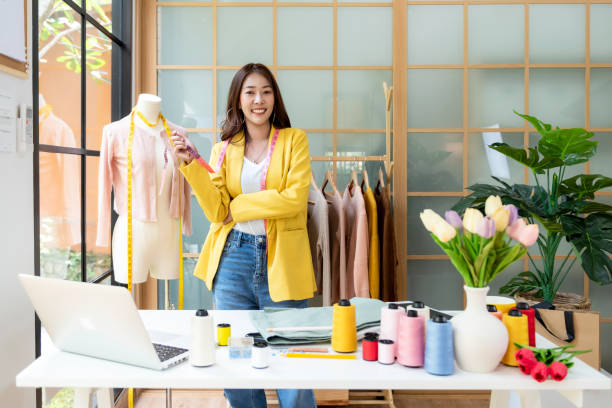 dona de negócios asiáticas jovens estilistas trabalhando em seu designer no showroom, - small business fashion designer young adult clothing - fotografias e filmes do acervo