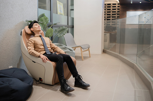 Asian businessman relaxing on massage chair in office