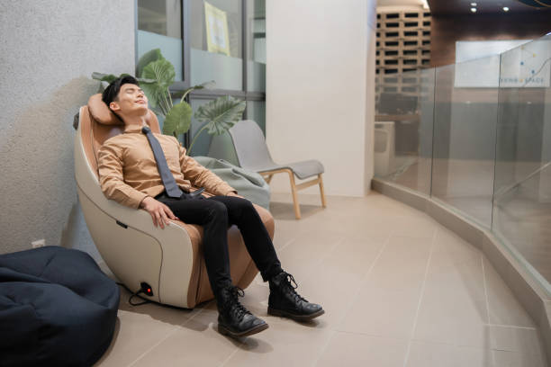 Asian businessman relaxing on massage chair in office stock photo