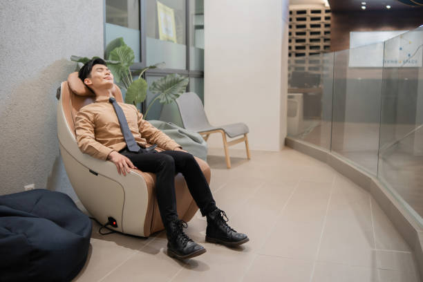 asian businessman relaxing on massage chair in office - ding imagens e fotografias de stock