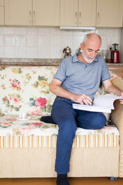 istock Handsome man sitting on sofa at home with books and doing homework 1412663814