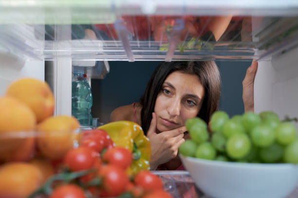 istock Woman looking in the fridge and thinking 1412665630