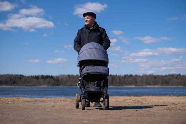 istock Grandfather walking with a baby stroller on cold and gloomy spring day 1412665695