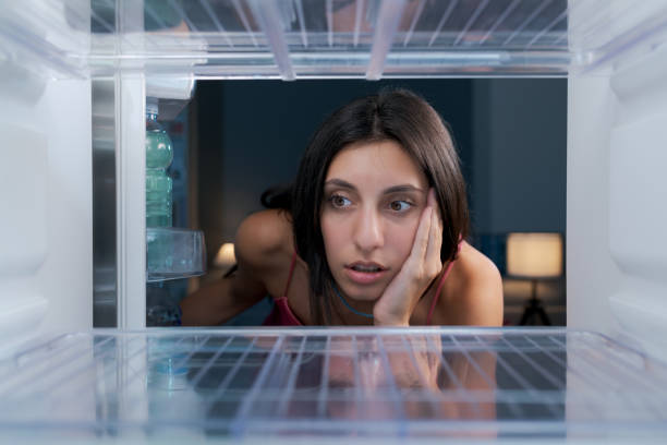 istock Shocked woman looking in her empty fridge 1412665889