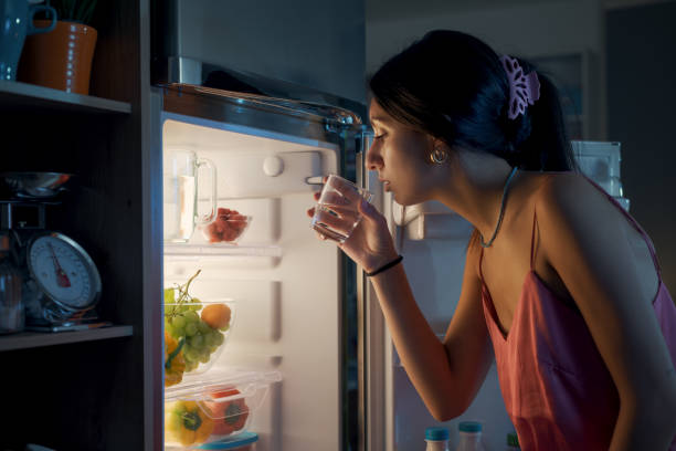 istock Thirsty woman looking in the fridge at night 1412666685