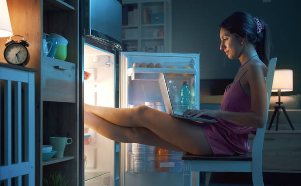 istock Woman cooling herself in front of the open fridge 1412666905