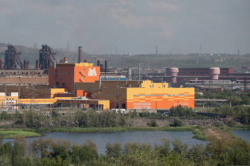 Magnitogorsk, Russia - 25 July 2021: Orange factory building with logo of MMK - Magnitogorsk Metal and Steel Works