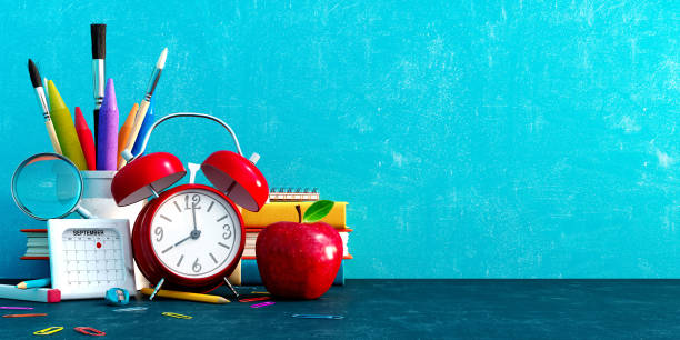 istock Ready for school, Back to school concept. Alarm clock with pencils and school accessory on blue chalkboard background 1412668337