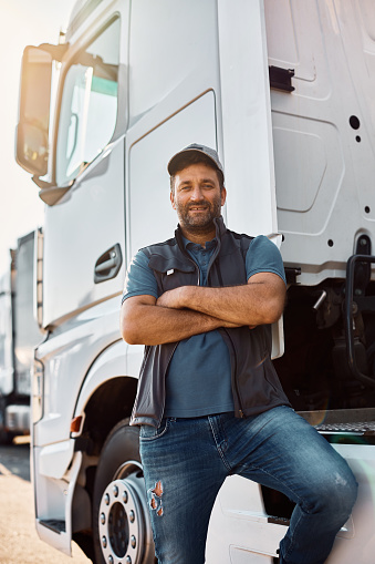 Happy truck driver standing with arms crossed and looking at camera.