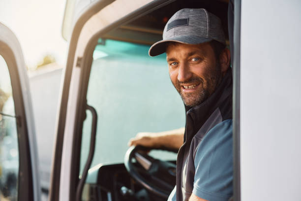 istock Happy truck driver behind steering wheel looking at camera. 1412671503