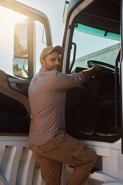 istock Young driver getting into truck cabin and looking at camera. 1412672636