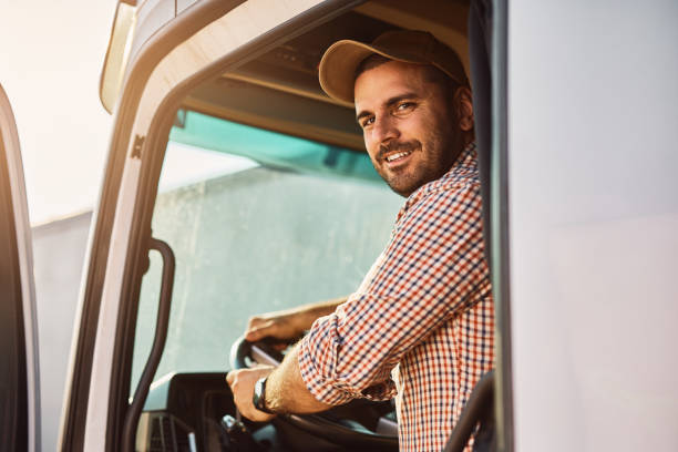istock Young truck driver behind steering wheel in cabin looking at camera. 1412672880