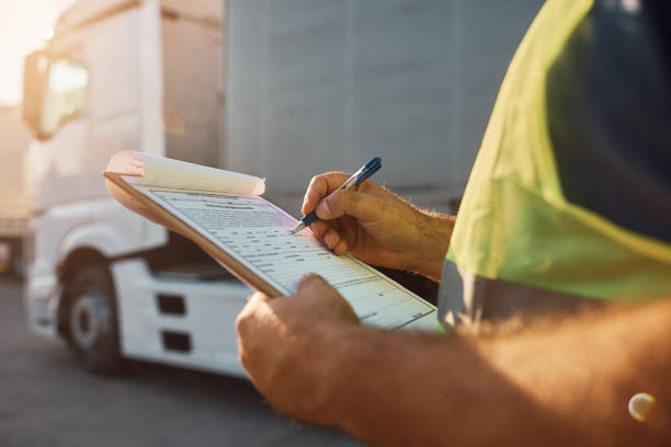 Close up of trucking dispatcher going through checklist on parking lot. stock photo