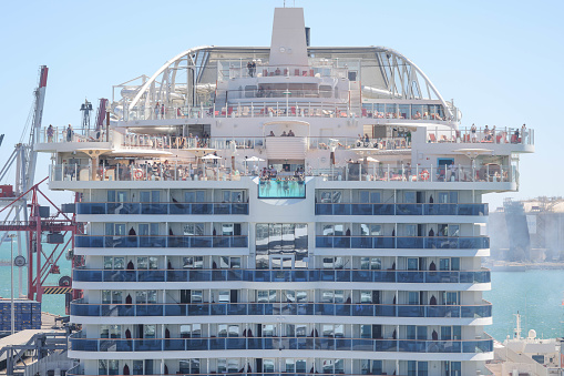 10th June, 2022 - Relaxed, happy and excited cruise ship passengers waving and swimming in an aft infinity pool as they sail away from Barcelona Port in the 2021 AIDAcosma a state-of-the-art LNG-powered mega cruise ship