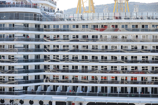 10th June, 2022 - Relaxed, happy and excited cruise ship passengers waving from their balcony staterooms as they sail away from Barcelona Port